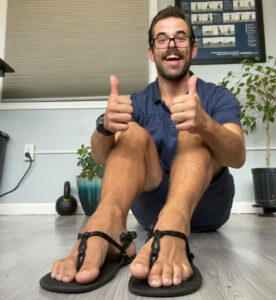 Man sitting down wearing sandals and giving a thumbs up