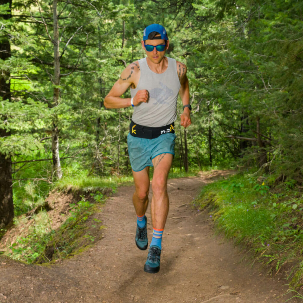 Front view of a man running on a dirt trail in the woods