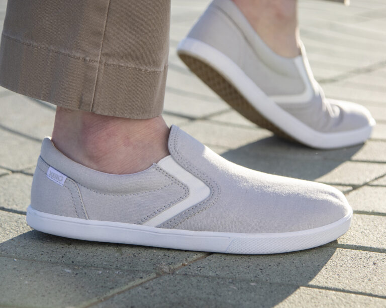 A man wearing Dillon Canvas Slip-ons standing on a brick walkway in the sun