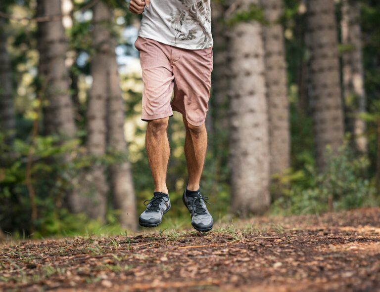 Waist-down view of a man running on a trail in the woods wearing Mesa Trail II trail running shoes