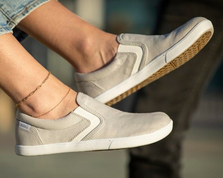 A close up shot of a woman wearing Dillon Canvas Slip-ons relaxing with her shoes comfortably resting in the air